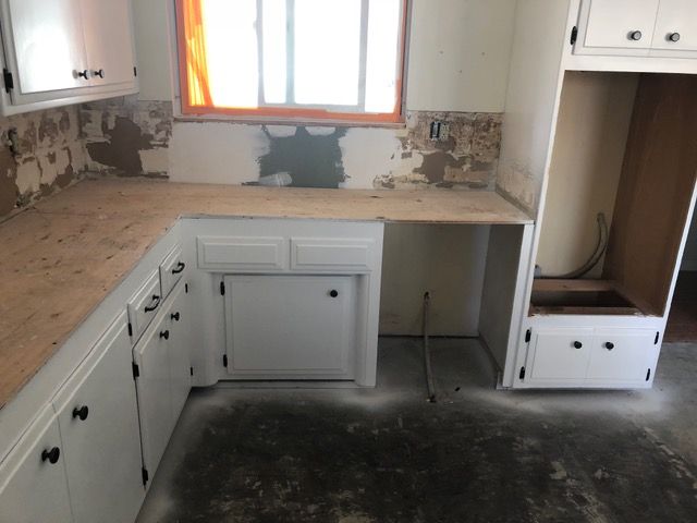 Unfinished white kitchen with bare countertops, window, and open cabinet spaces under construction