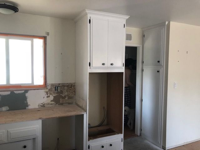Small kitchen under renovation with white cabinets, countertop, window, and unfinished backsplash.