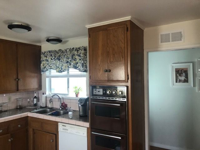 Small kitchen with wooden cabinets, window over sink, and built-in oven beside a doorway