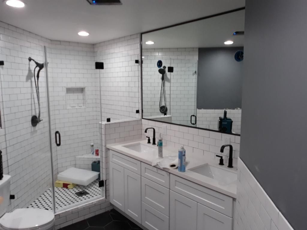 Modern bathroom with walk-in shower, white tile, double vanity, and large mirror