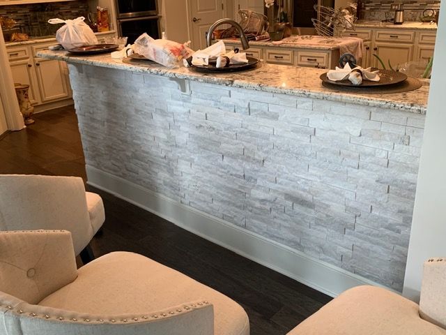Restaurant bar with stone front, dark wood floor, and round stools in a warm interior