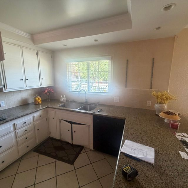 Bright kitchen with white cabinets, granite counters, tile floor, and a window over the sink.