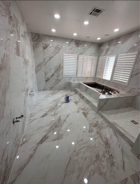 Marble-tiled kitchen under renovation with white shutters and a countertop island in progress