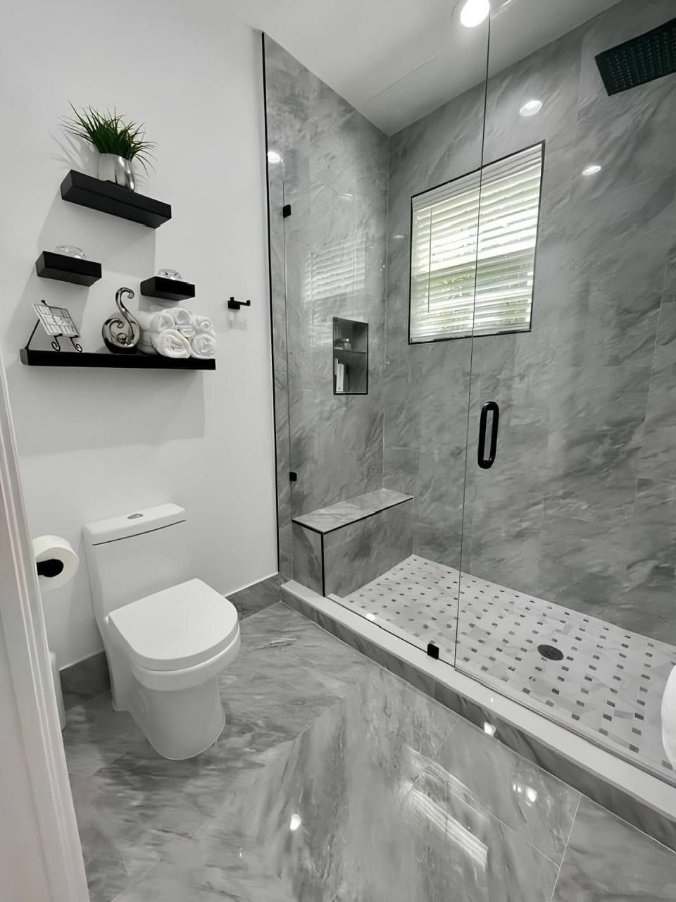 Modern white-tiled bathroom with glass walk-in shower and wall-mounted toilet