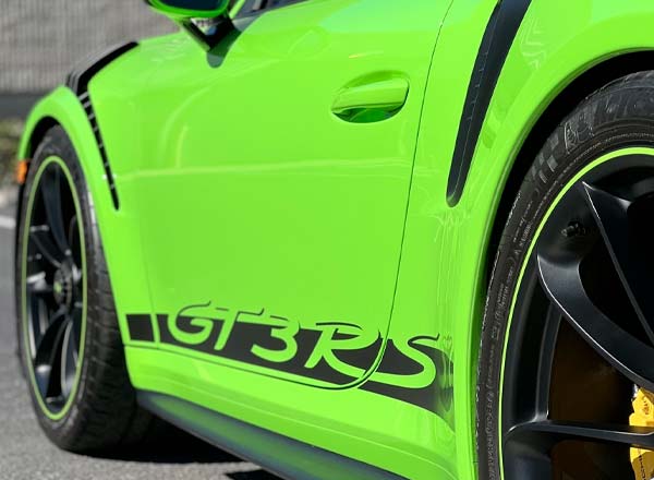 Green Porsche GT3 RS side view, black trim, black and yellow wheels.