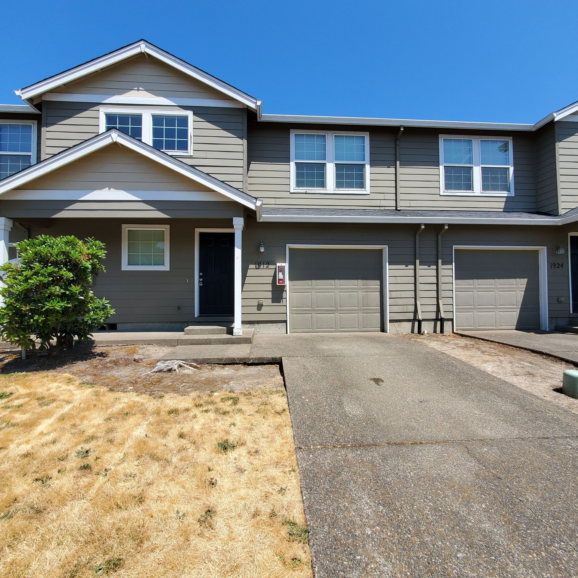 Meadowridge Townhomes in Monmouth Oregon – olive green front exterior with two garages, front door, and many windows.