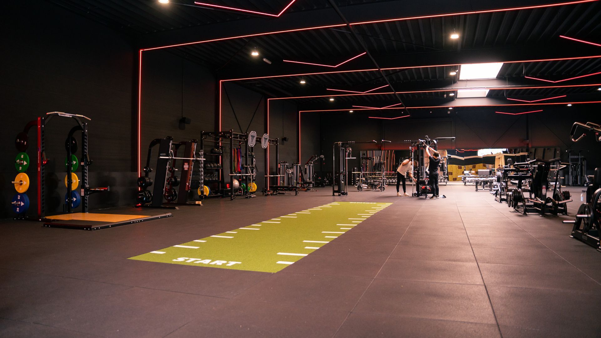 Interieur van een sportschool met fitnessapparatuur. Groene atletiekbaan op de vloer