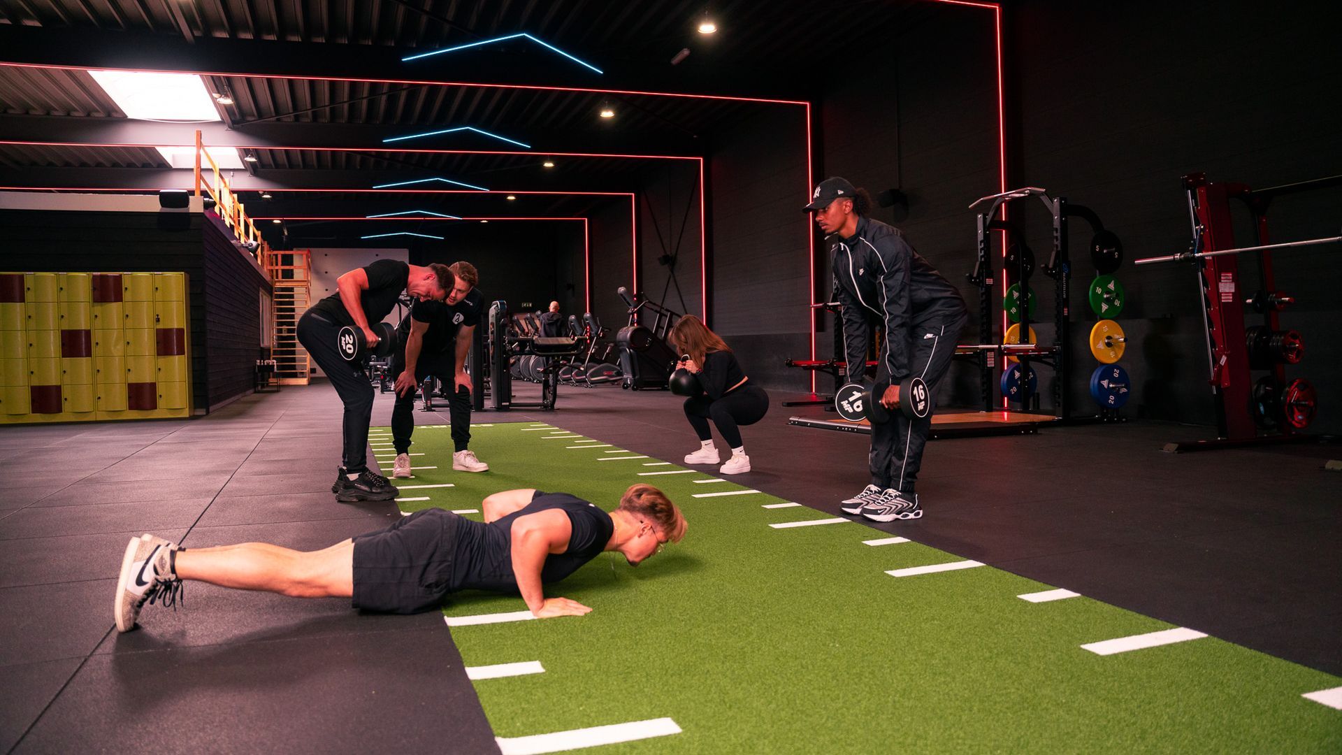 Mensen die aan het sporten zijn in een sportschool: de een doet push-ups, de ander deadlifts