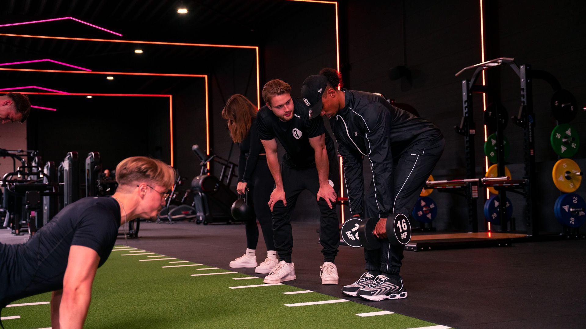 Mensen die onder begeleiding van trainers in een sportschool trainen.