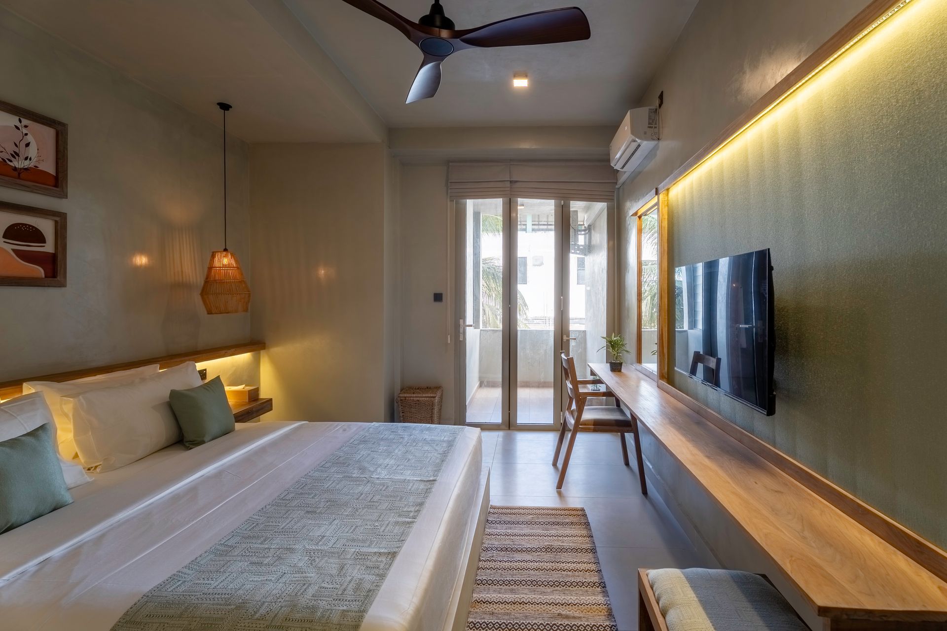 Modern bedroom with bed, wall-mounted TV, warm lighting, and balcony doors