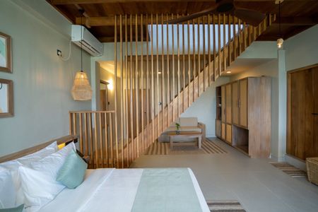 Modern bedroom with white bed, wood slat divider, and staircase in a bright minimalist interior