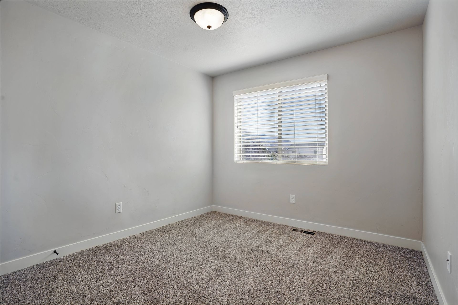 Empty room with gray walls, carpet, and a window with blinds.
