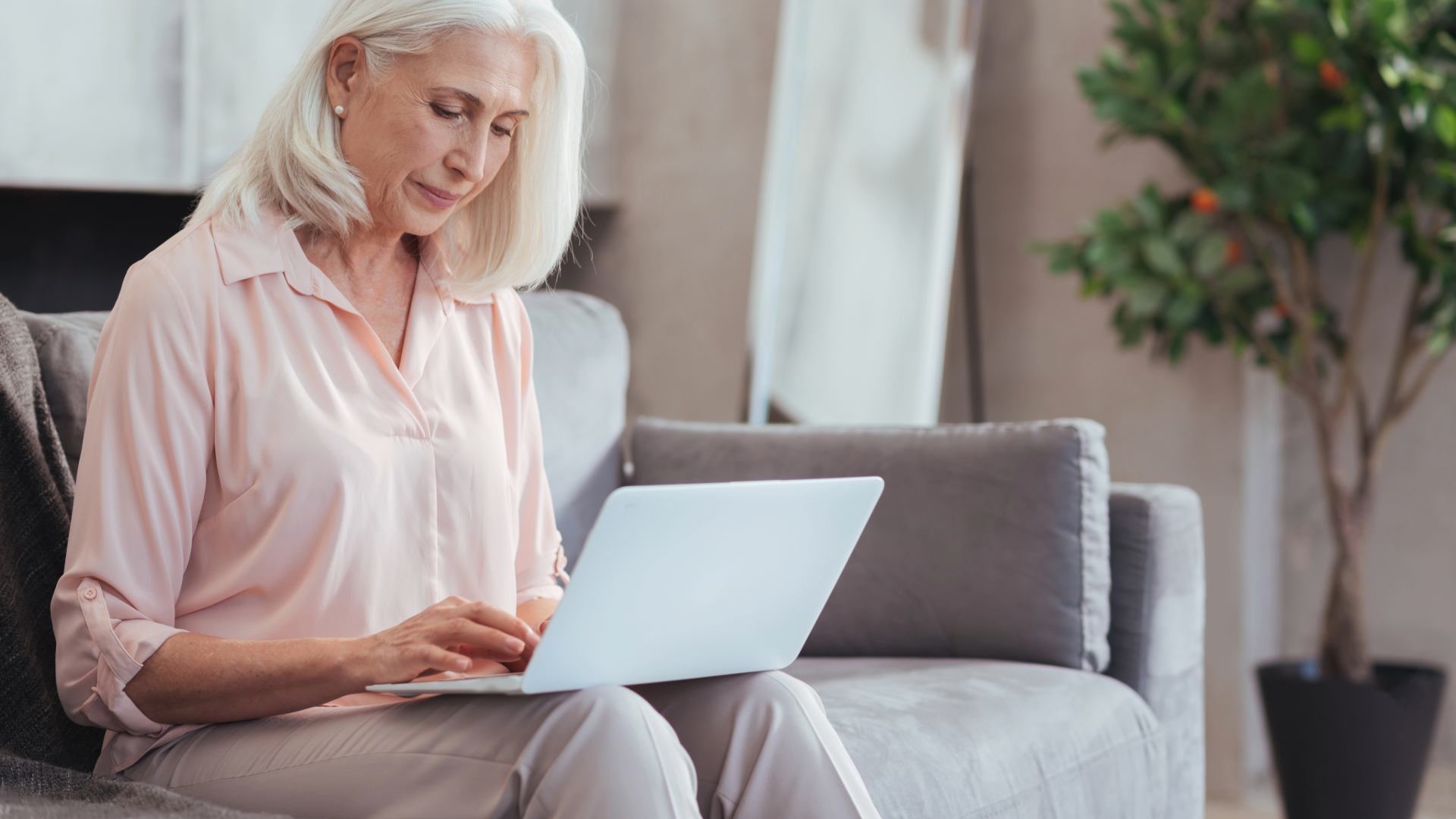 Woman using a laptop on a couch in a bright living room