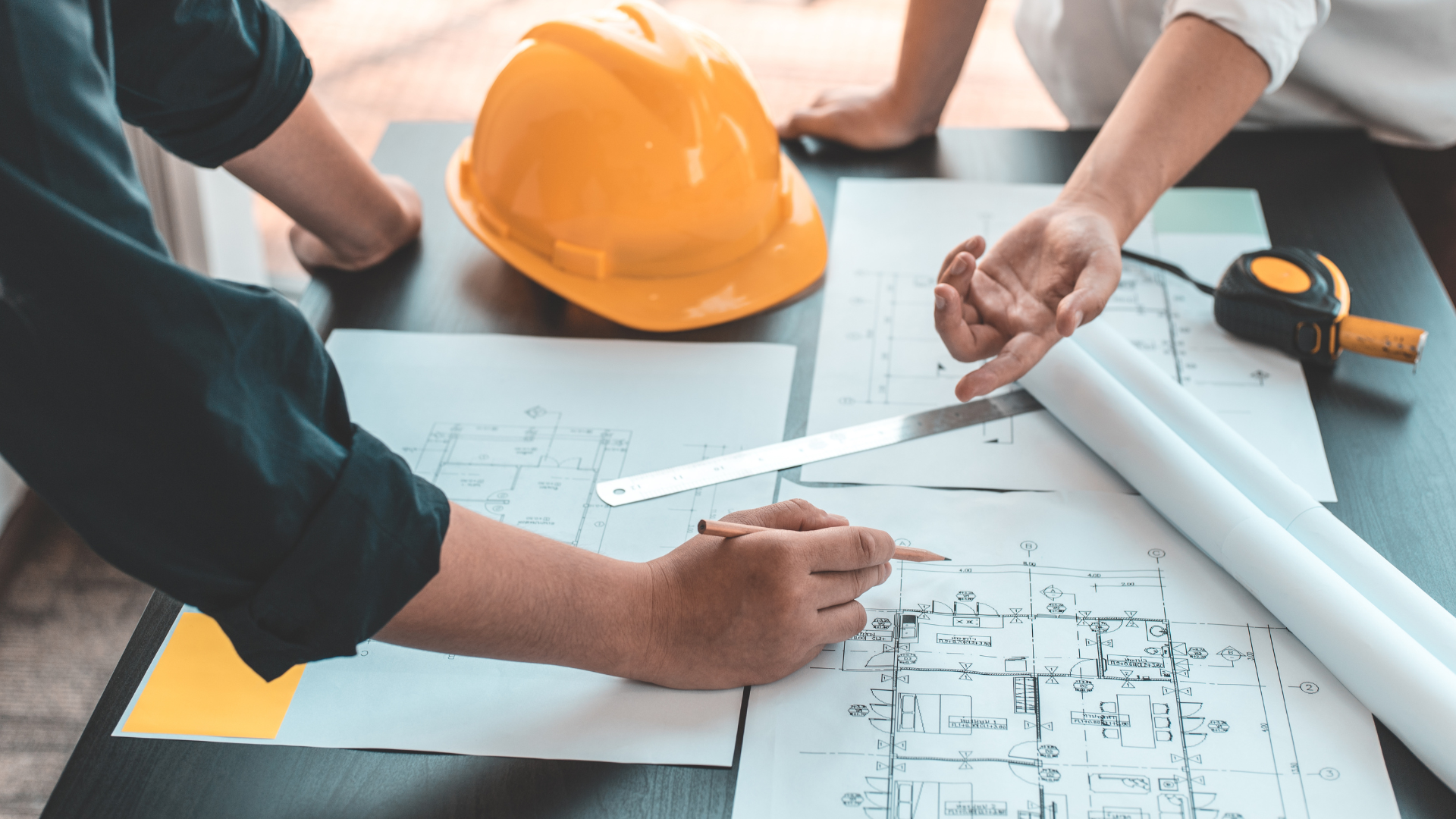 A group of people are sitting at a table looking at a blueprint.
