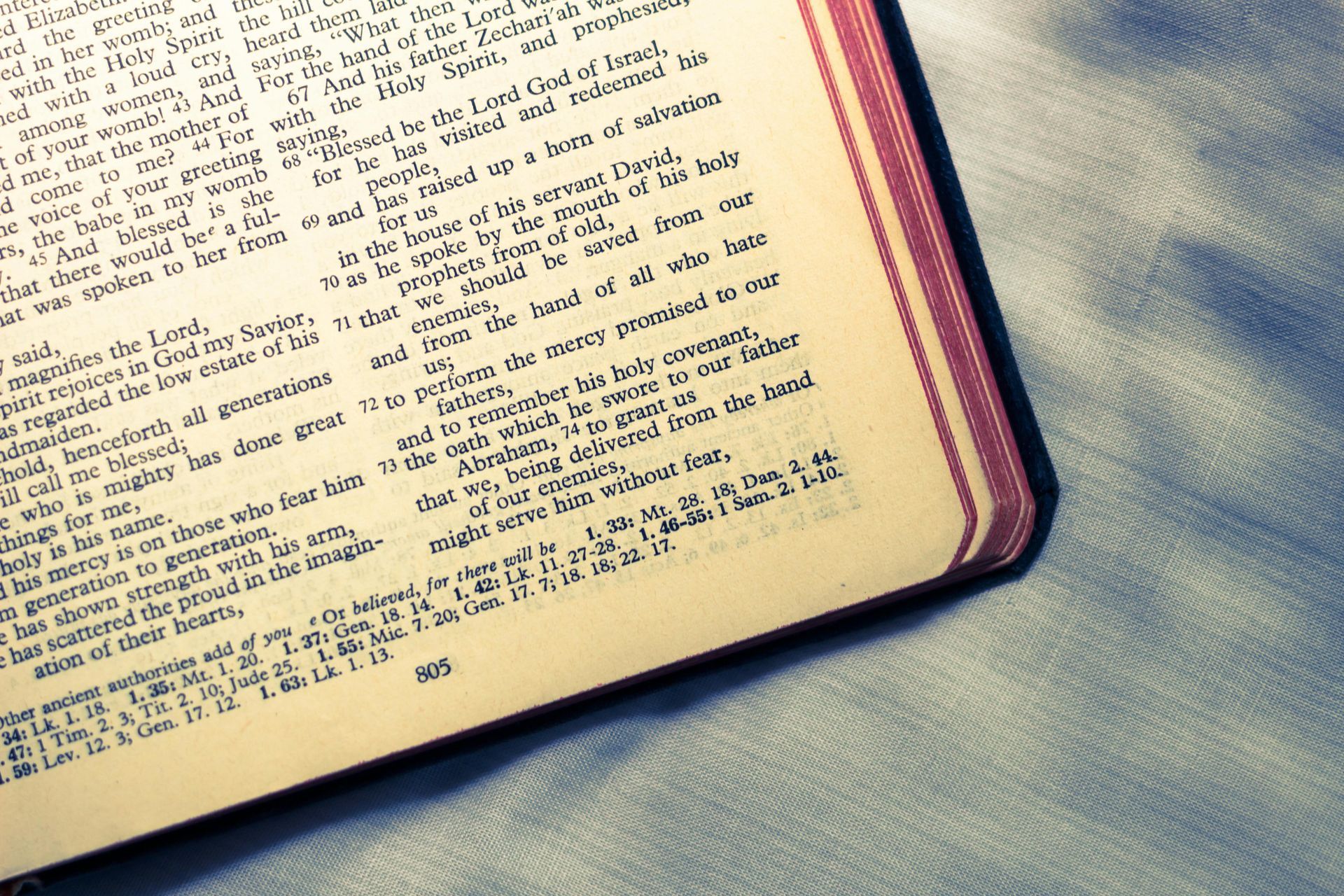 Open book with handwritten notes on a textured blue-gray fabric surface