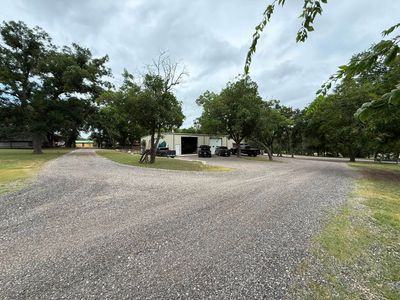 Gravel lot with a small building and trees under a cloudy sky