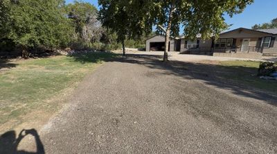 Gravel lot with a small building and trees under a cloudy sky