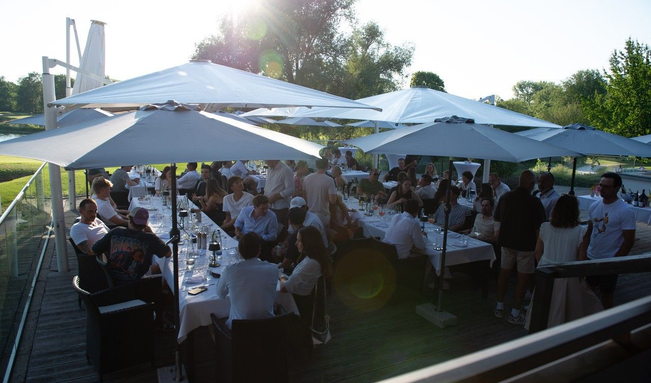 Die Terrasse des Platzhirsch Restaurants in Olching während eines Events. Mensche unterhalten sich an den Tisch, während Kellner bedienen