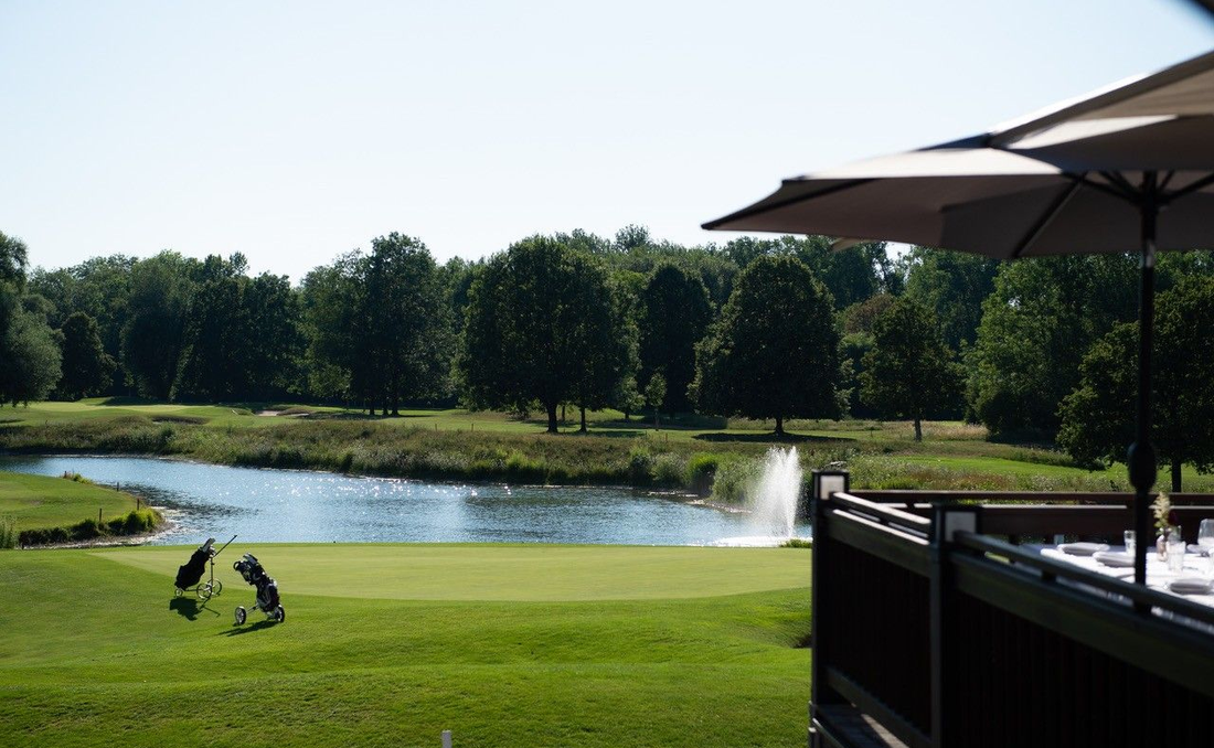 Panorama-Blick auf den Golfplatz von der Terrasse des Restaurant Olching, mit See und Bäumen