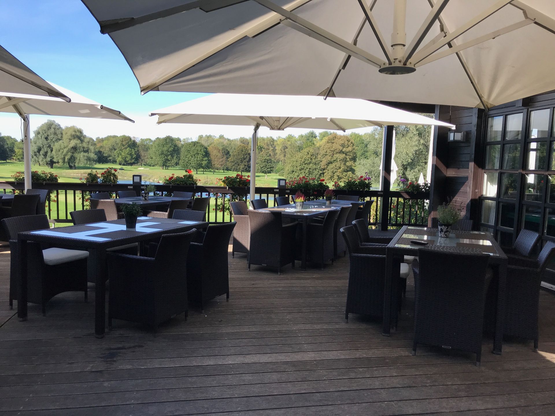 Tische und Stühle auf der Terrasse des Restaurant Platzhirsch im Schatten der aufgespannten Sonnenschirme