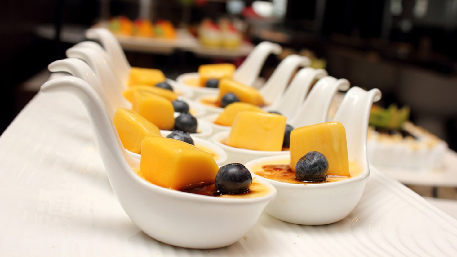 Dessert in kleinen löffelförmigen Schalen, bestehend aus Creme und Früchten