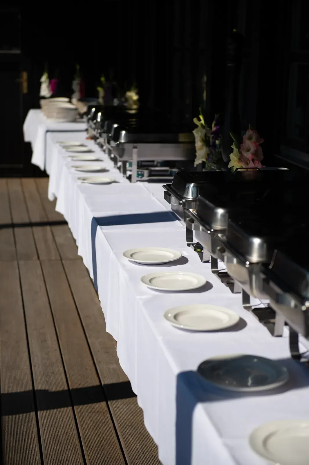 Buffet mit Chafing Dishes und Blumen auf der Terrasse des Platzhirsch