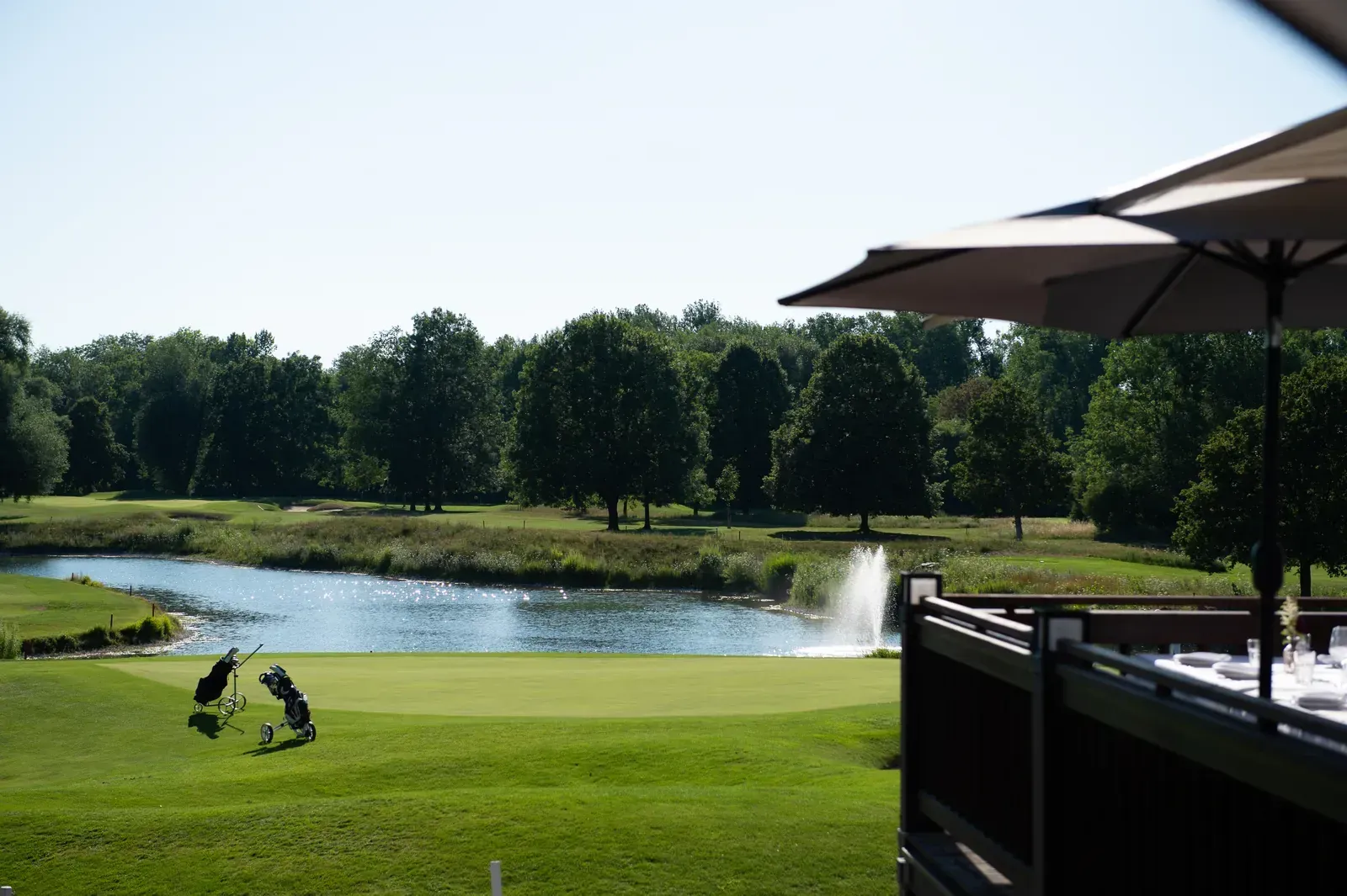 Blick von der Terrasse des Platzhirsch auf Golfplatz Olching mit Teich und Fontäne