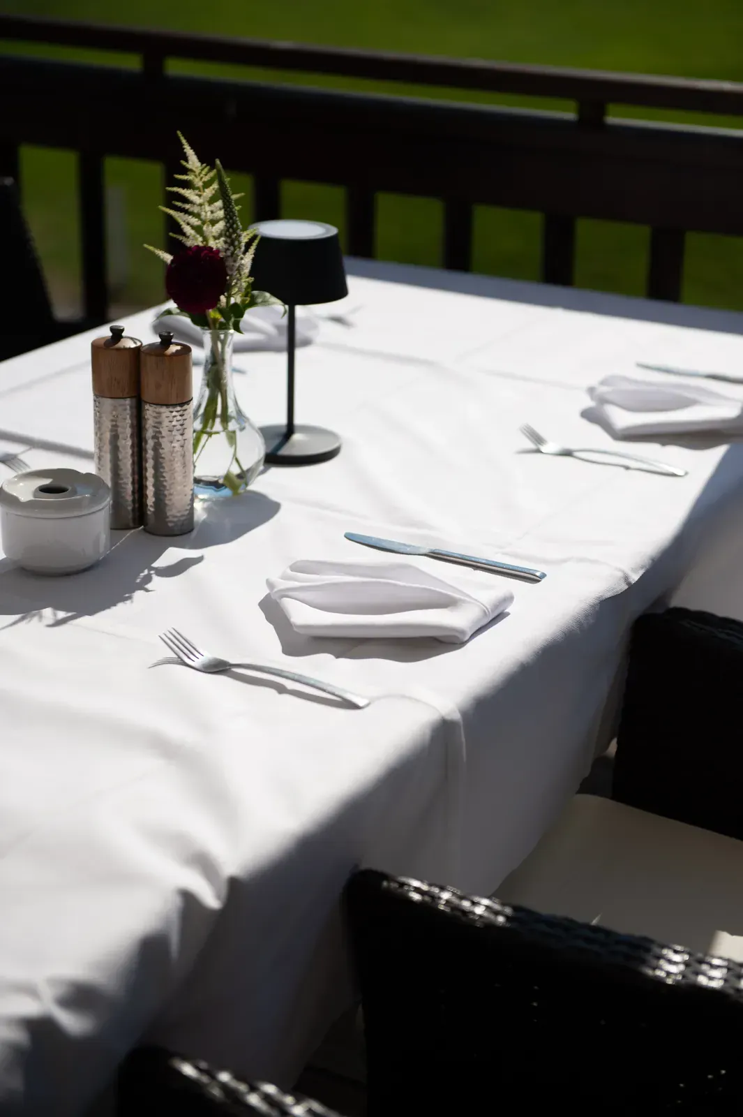 Weiß eingedeckter Tisch mit Blumen und Tischleuchte auf der Terrasse