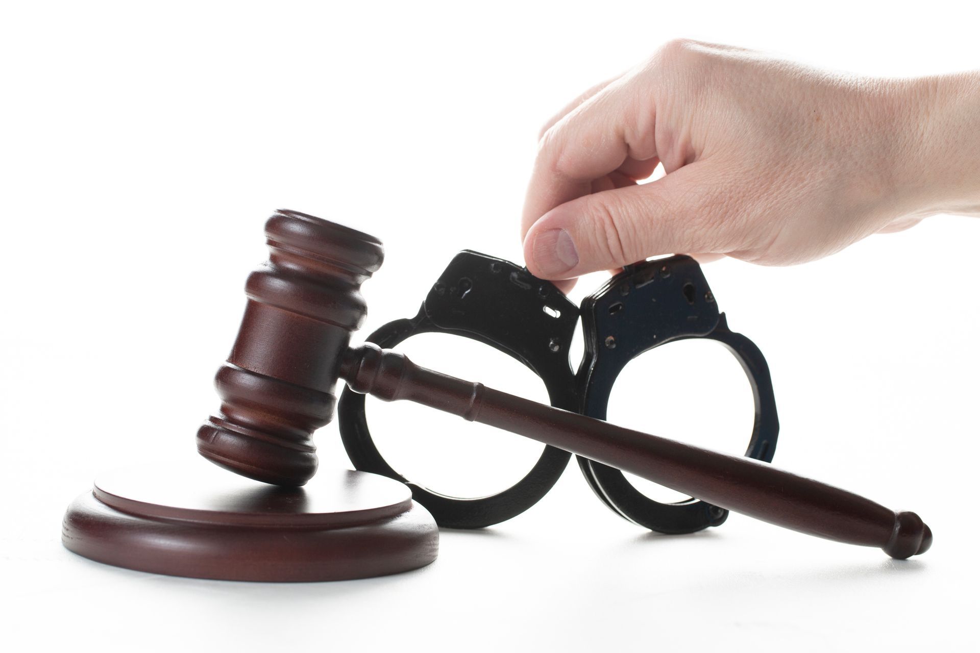 Judge’s gavel and handcuffs on a white background, symbolizing criminal defense.