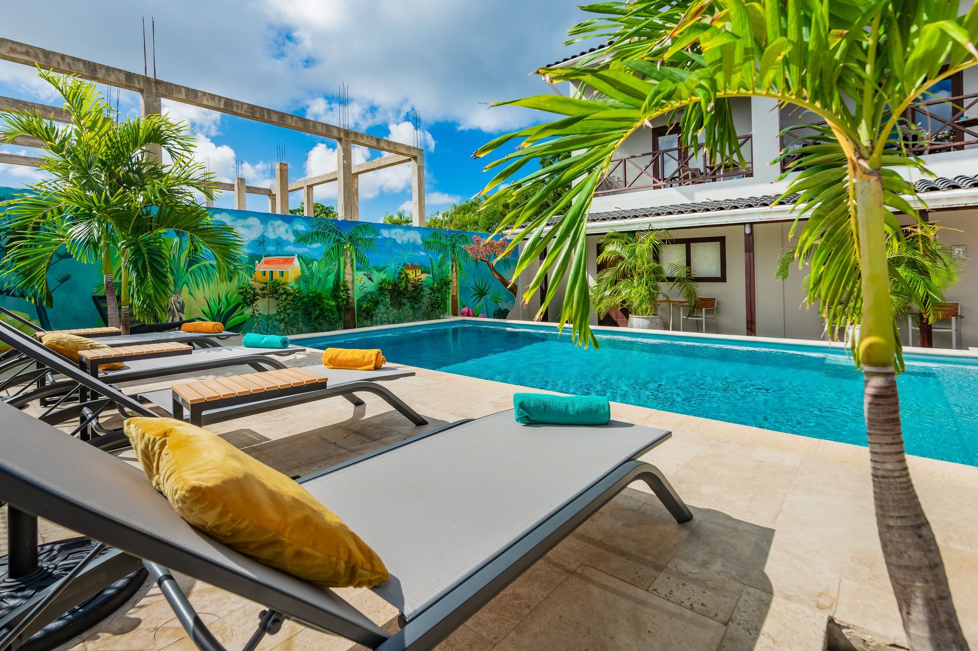 A large swimming pool surrounded by lawn chairs and palm trees.