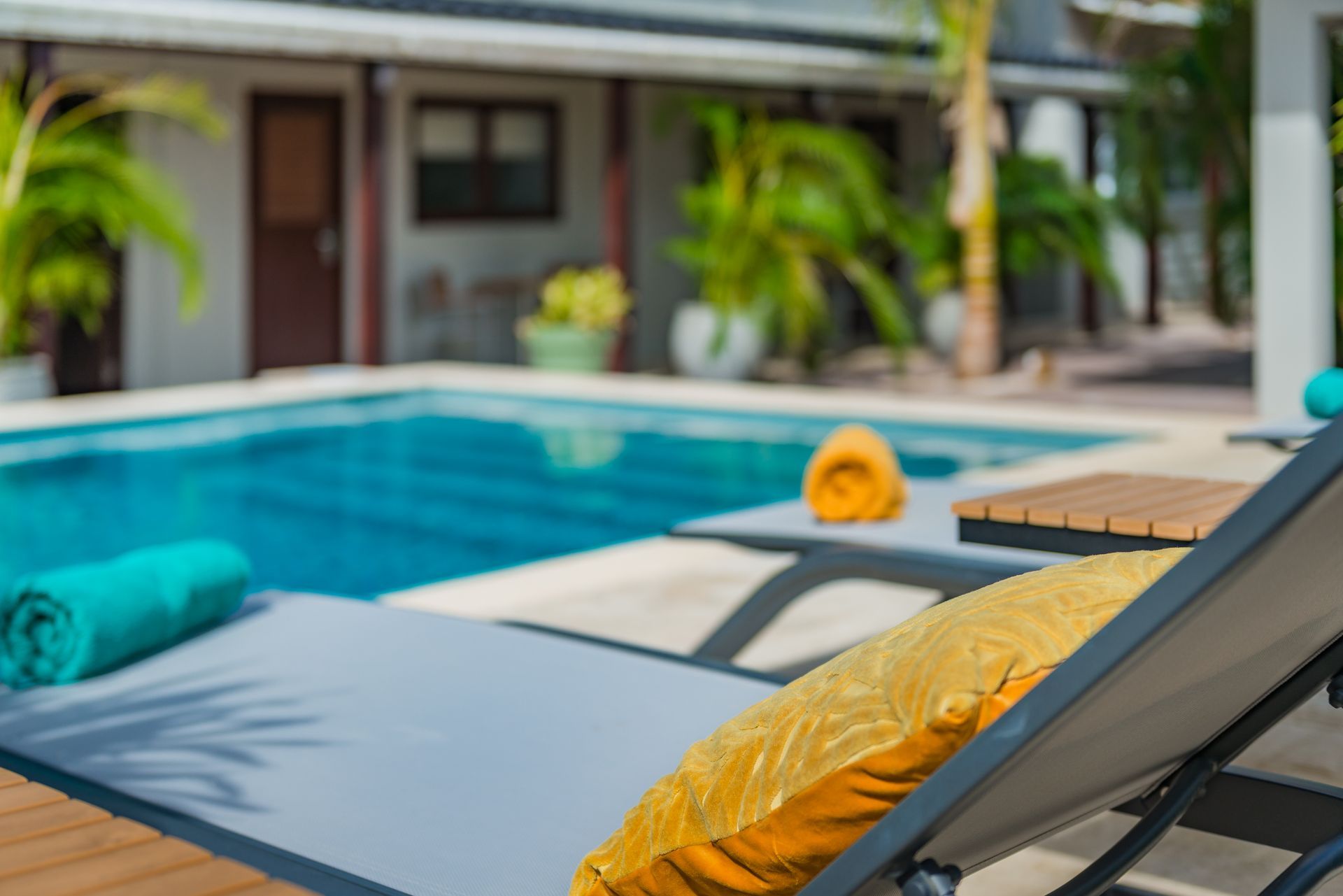 A swimming pool with lounge chairs and towels in front of it.