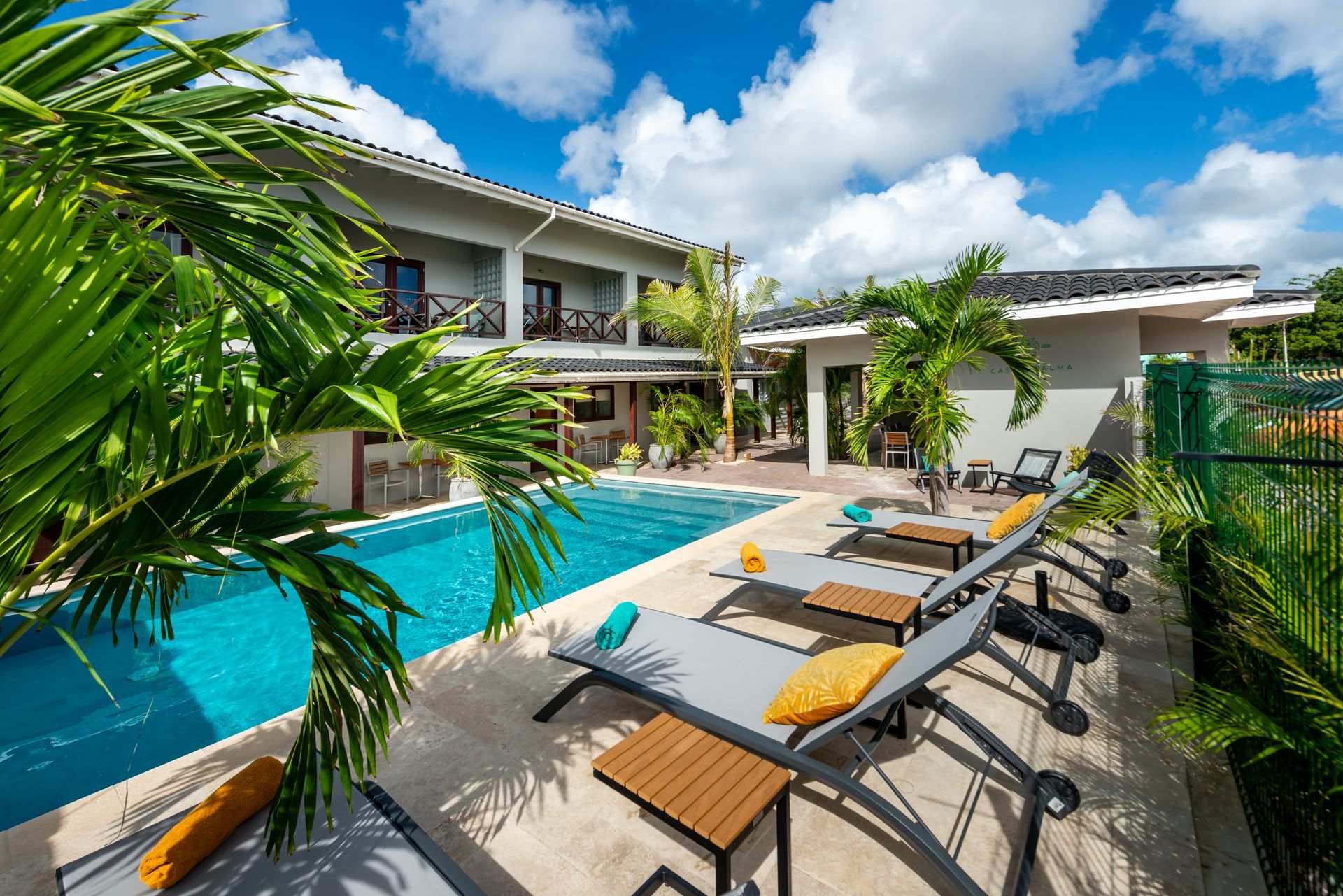 A large swimming pool surrounded by lounge chairs and palm trees