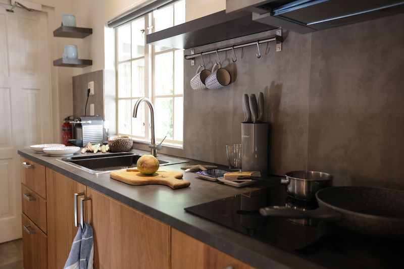 A kitchen with a sink , stove , and pots and pans on the counter.