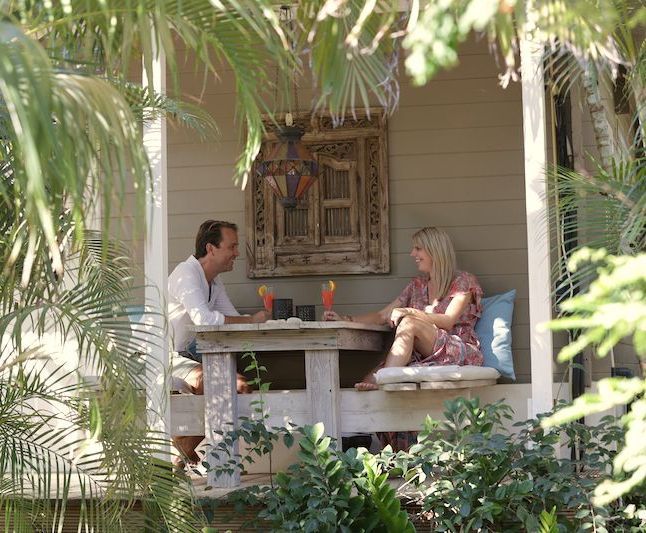 A man and a woman are sitting at a table on a porch.