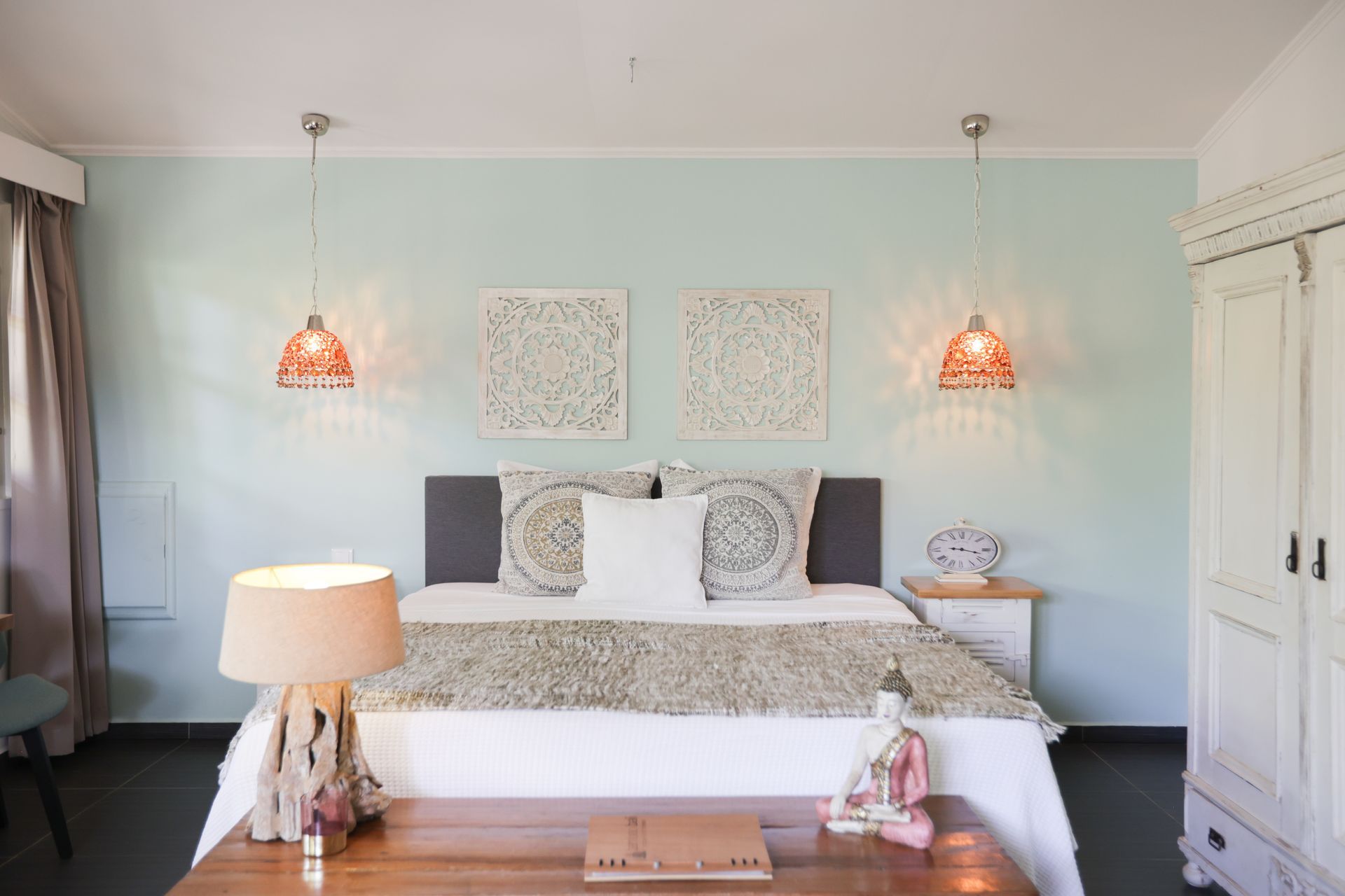 A bedroom with a king size bed , a table , a lamp and a wardrobe.