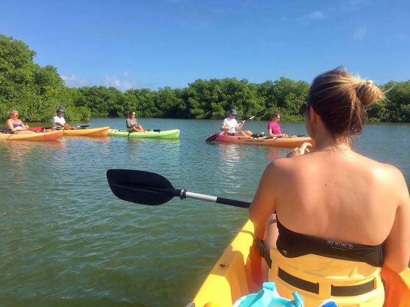 A woman is paddling a yellow kayak on a lake