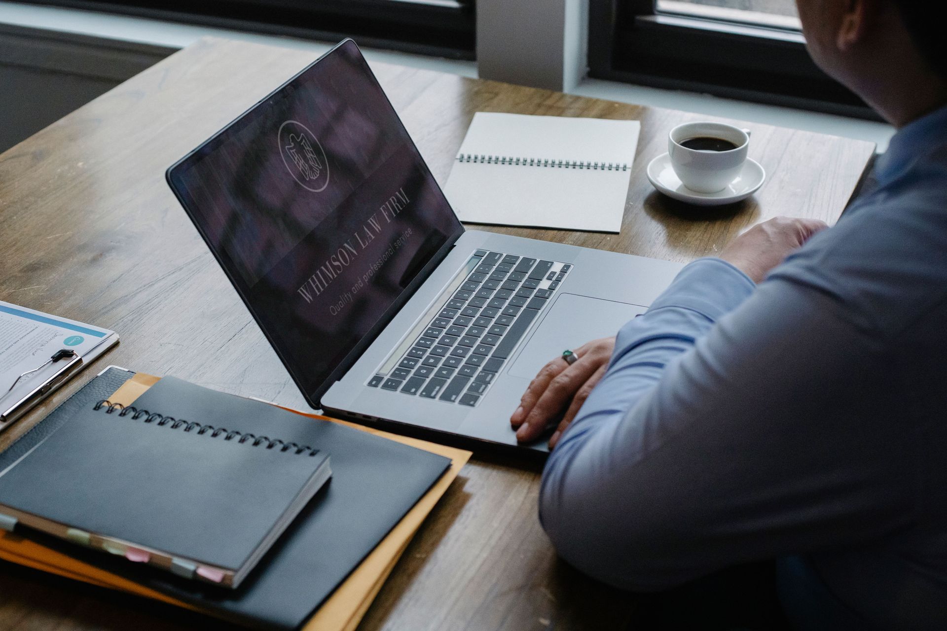 Elderly couple smiles while looking at a laptop on a couch. Woman has arm around man.