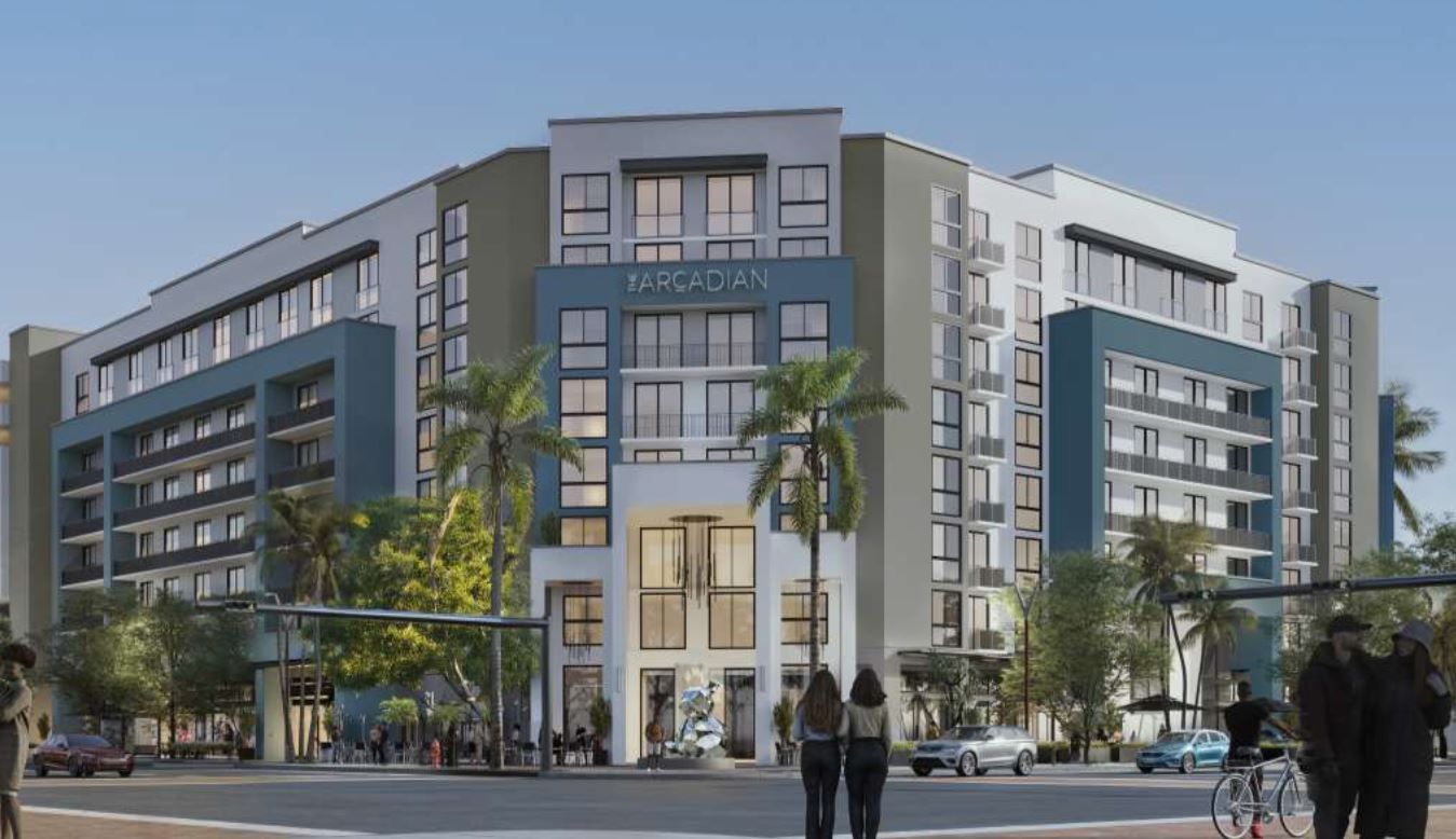 Modern multi-story apartment building with glass balconies and palm trees at street level at The Arcadian in Fort Lauderdale