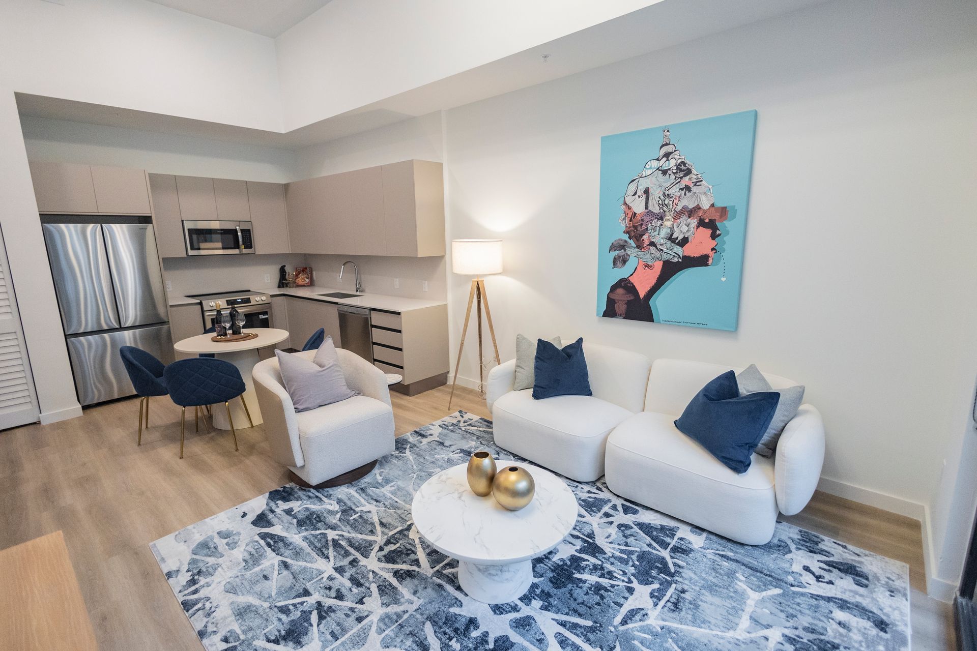 Modern living room with white sofa, blue rug, coffee table, and open kitchen in the background at The Arcadian in Fort Lauderdale
