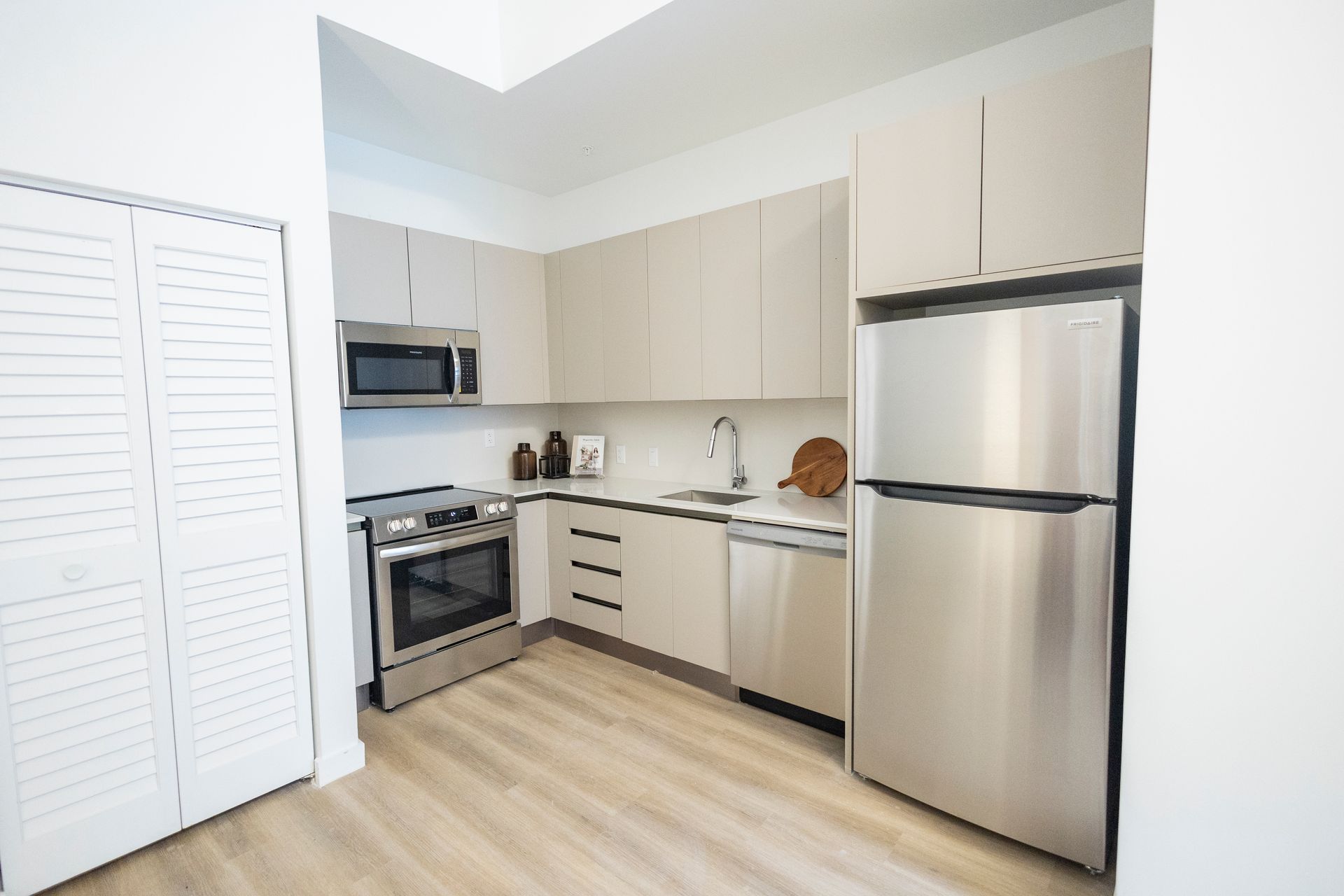 Bright modern kitchen with stainless steel appliances, white cabinets, and light wood flooring at The Arcadian