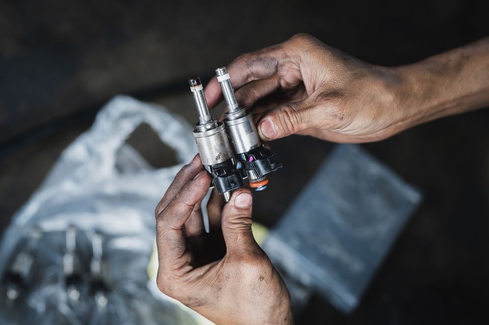 Mechanic Holding Two Fuel Injectors — AWS Mechanical in Stuart Park, NT