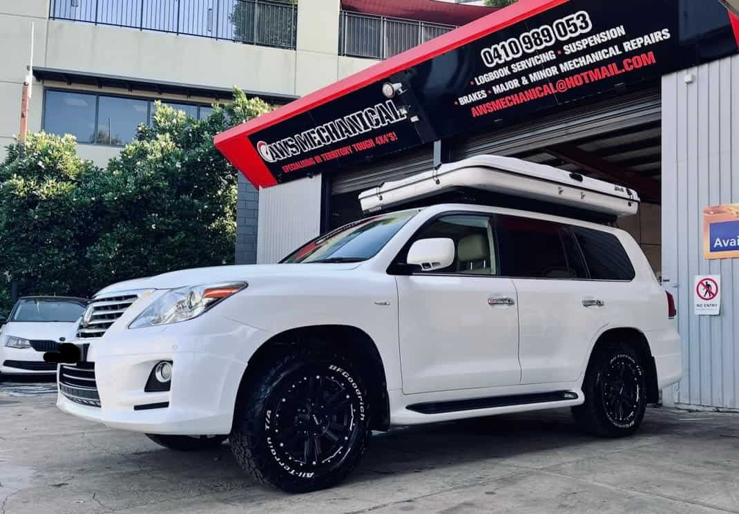 A White Suv With a Tent on Top of It is Parked in Front of a Building — AWS Mechanical in Stuart Park, NT