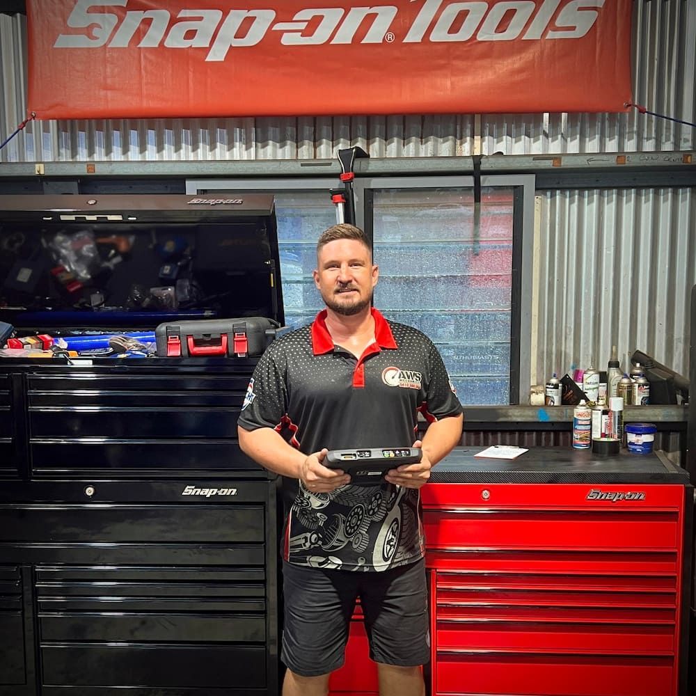 A Man holding A Device with Toolboxes behind him — AWS Mechanical in Stuart Park, NT