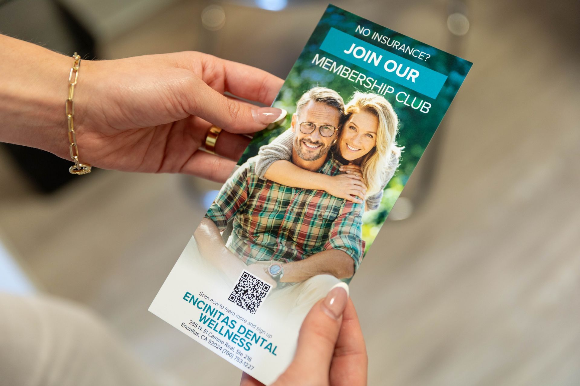 Hands holding a brochure with a smiling couple and the text “JOIN OUR CLUB” over a beach background