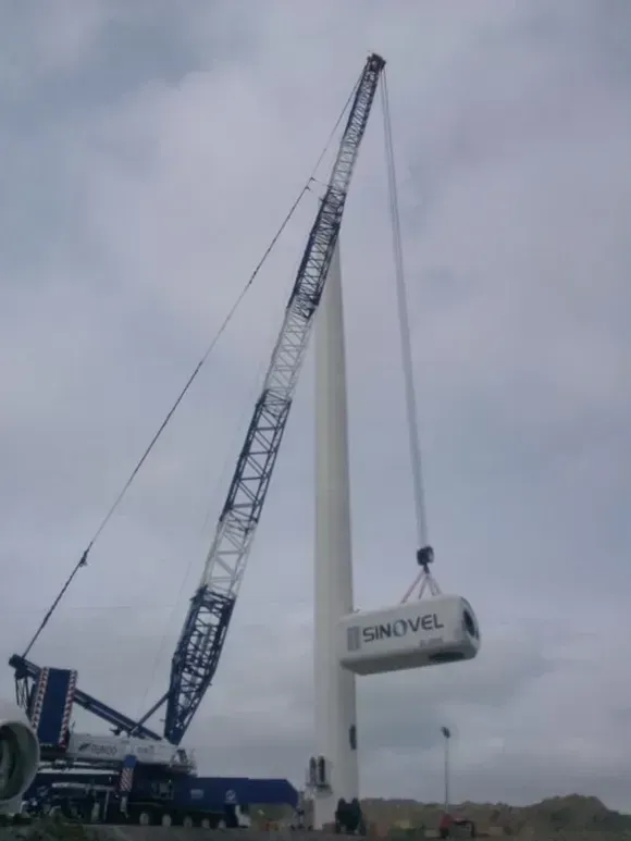 Una gru sta sollevando un container su cui è scritto sinovel