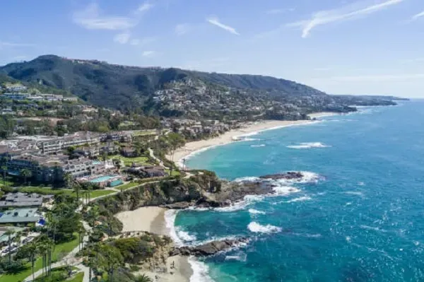 An aerial view of a beach surrounded by mountains and a body of water.