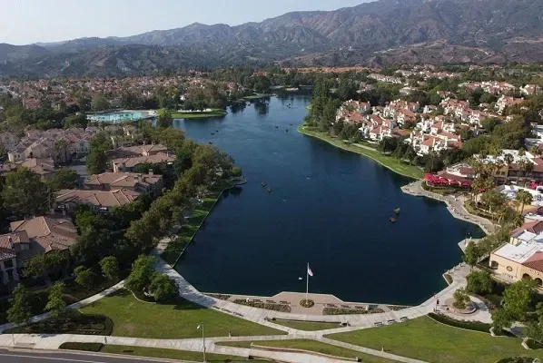 An aerial view of a lake in a residential area with mountains in the background.