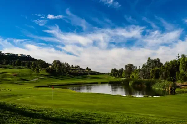 A golf course with a pond in the middle of it.