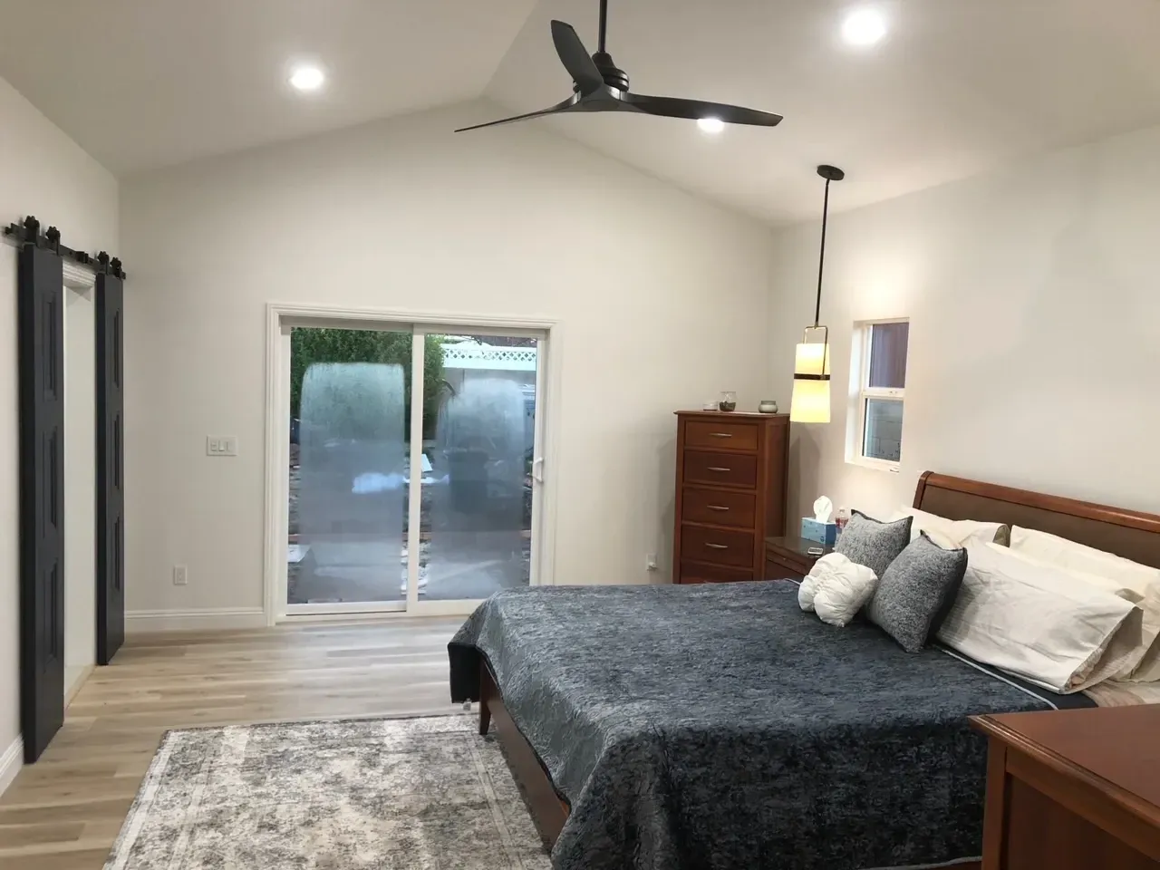 A bedroom with a large bed and a ceiling fan.