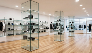 Luminoso negozio di abbigliamento minimalista con pavimenti in legno, vetrine e scaffali per abiti lungo le pareti.